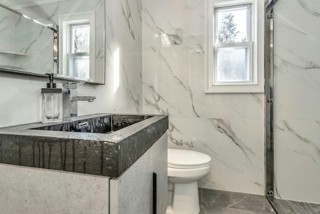 bathroom featuring a shower with shower door, sink, and toilet