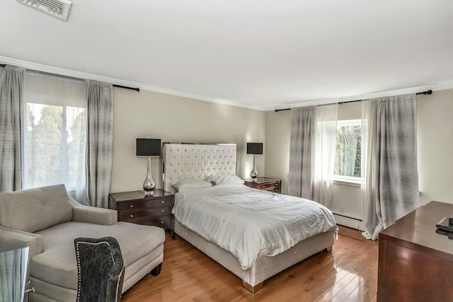 bedroom featuring a baseboard radiator, light hardwood / wood-style flooring, and ornamental molding