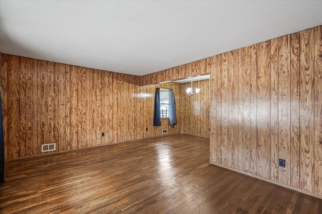 empty room featuring wooden walls and dark wood-type flooring