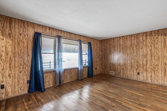 unfurnished room with wood walls and dark hardwood / wood-style flooring