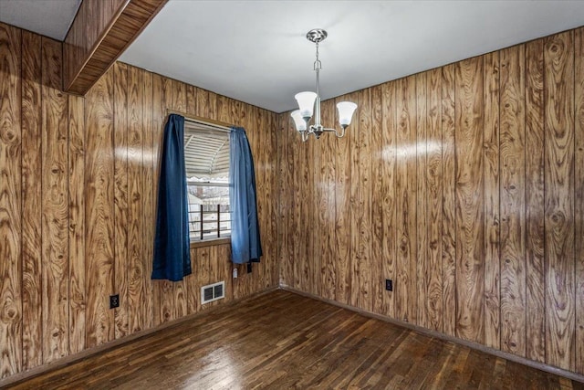 unfurnished dining area with a chandelier, wood walls, and dark hardwood / wood-style flooring