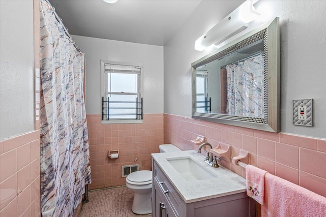 bathroom with curtained shower, tile patterned flooring, vanity, tile walls, and toilet