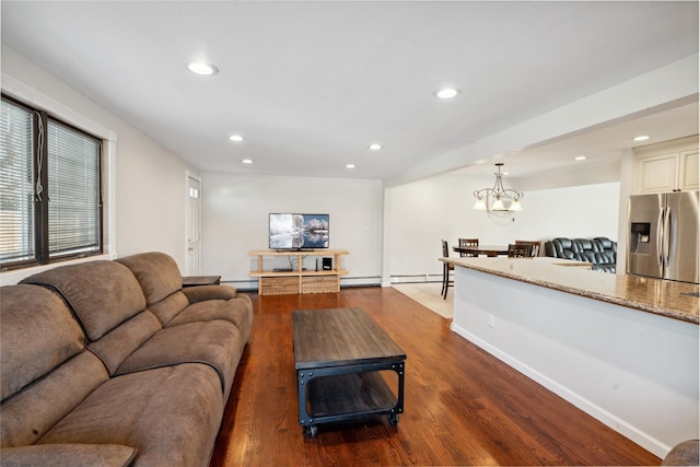 living room featuring a baseboard heating unit, dark wood-type flooring, and a chandelier