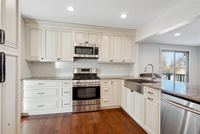 kitchen with dark hardwood / wood-style floors, appliances with stainless steel finishes, light stone counters, and sink