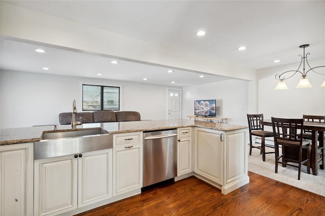 kitchen with light stone countertops, dishwasher, sink, hanging light fixtures, and dark hardwood / wood-style floors