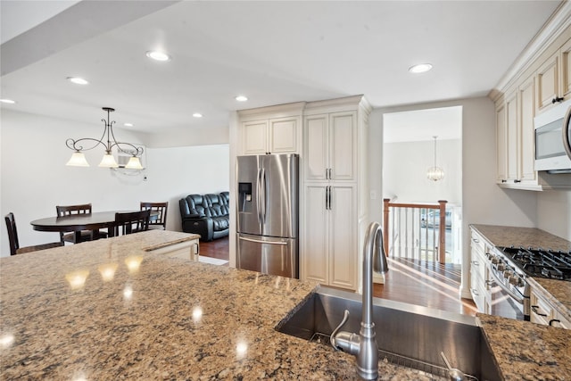 kitchen featuring sink, pendant lighting, stone counters, and stainless steel appliances