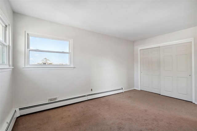 unfurnished bedroom featuring baseboard heating, carpet, and a closet