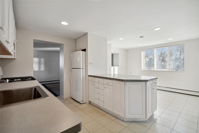 kitchen with white fridge, baseboard heating, white cabinets, and sink