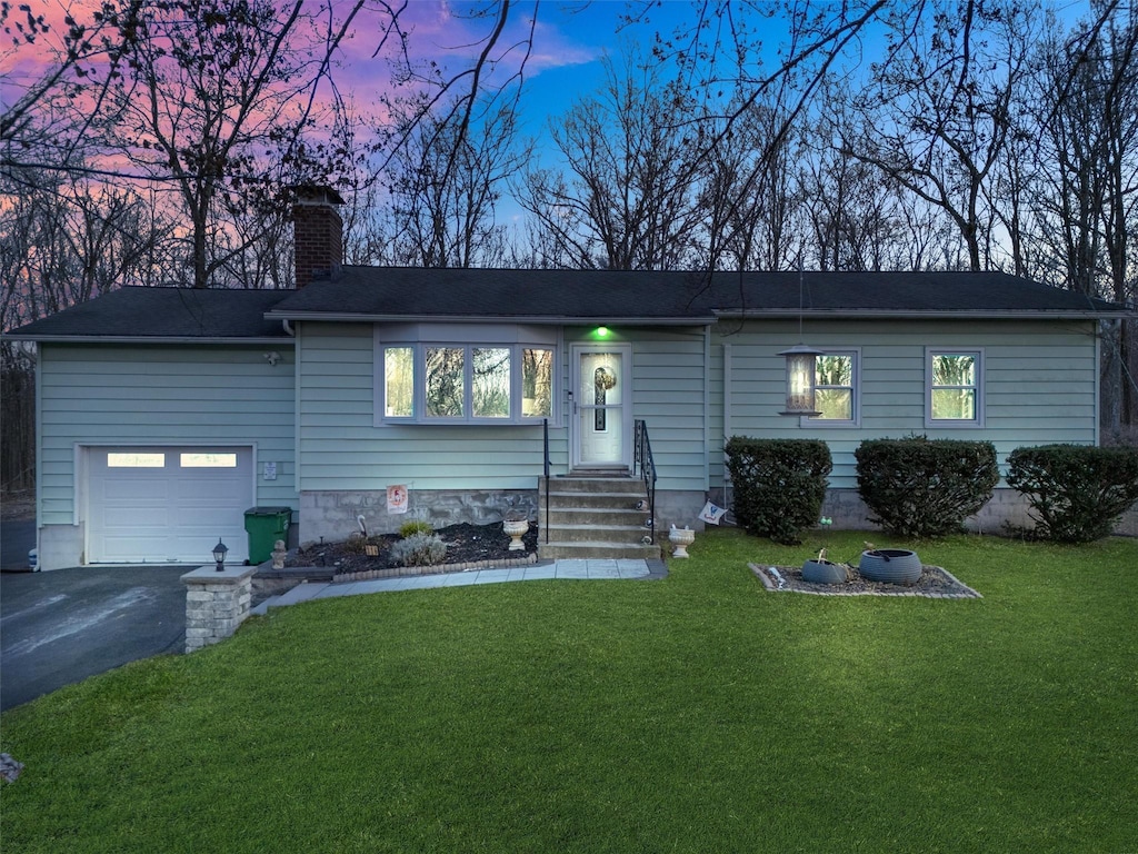 ranch-style house with a garage and a yard