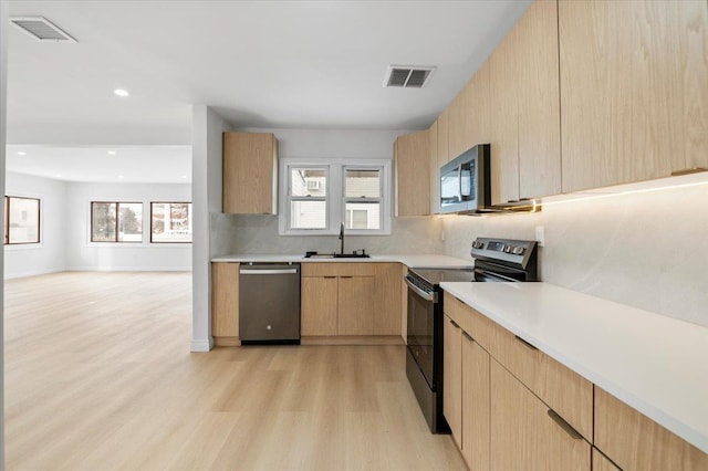 kitchen featuring sink, decorative backsplash, stainless steel appliances, light brown cabinets, and light hardwood / wood-style flooring