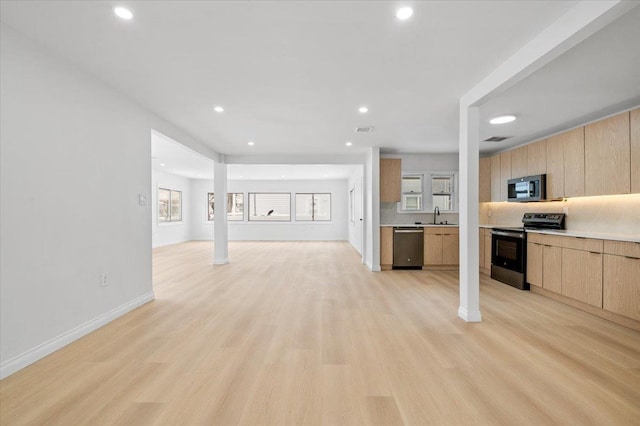 kitchen featuring light brown cabinetry, sink, backsplash, stainless steel appliances, and light wood-type flooring