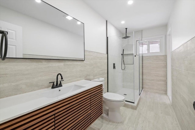 bathroom featuring vanity, toilet, a shower with shower door, and tile walls