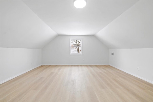 additional living space featuring lofted ceiling and light wood-type flooring