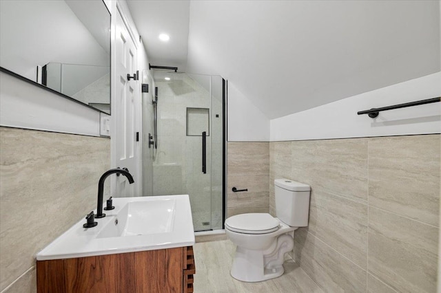 bathroom with toilet, vaulted ceiling, tile walls, vanity, and a shower with door