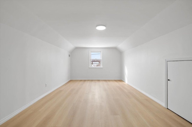 additional living space featuring vaulted ceiling and light hardwood / wood-style flooring