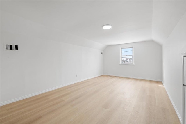 additional living space with vaulted ceiling and light wood-type flooring