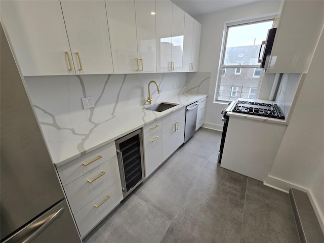 kitchen with sink, appliances with stainless steel finishes, white cabinets, beverage cooler, and light stone counters