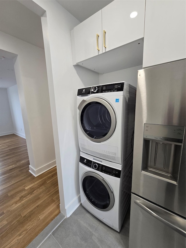 laundry area with stacked washer / drying machine and tile patterned floors