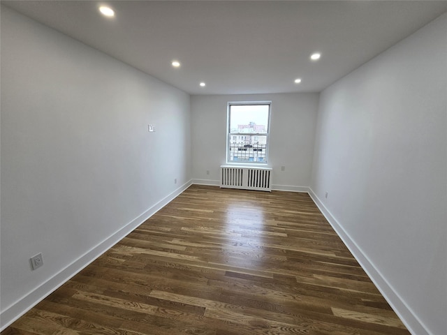 empty room with radiator and dark hardwood / wood-style flooring