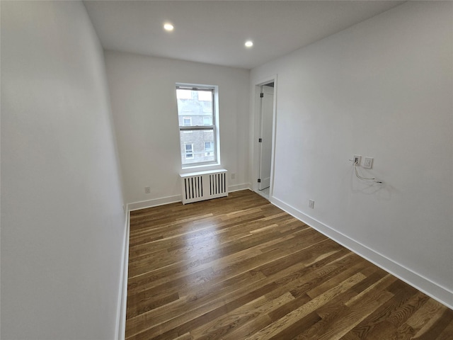 unfurnished room featuring dark hardwood / wood-style floors and radiator heating unit