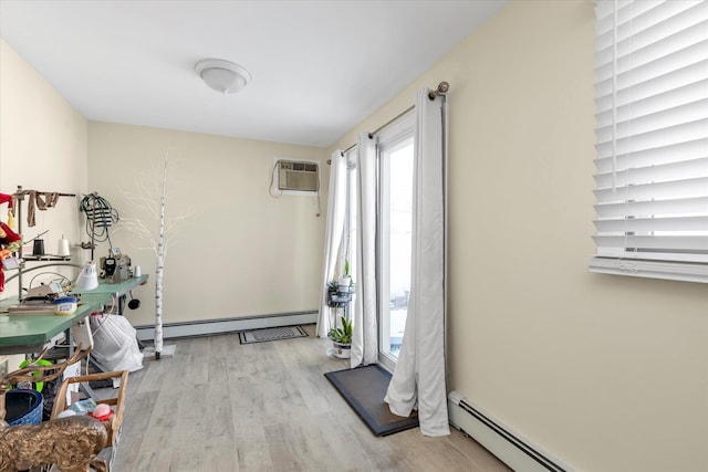 exercise area with a baseboard heating unit, a wall mounted air conditioner, and light hardwood / wood-style floors