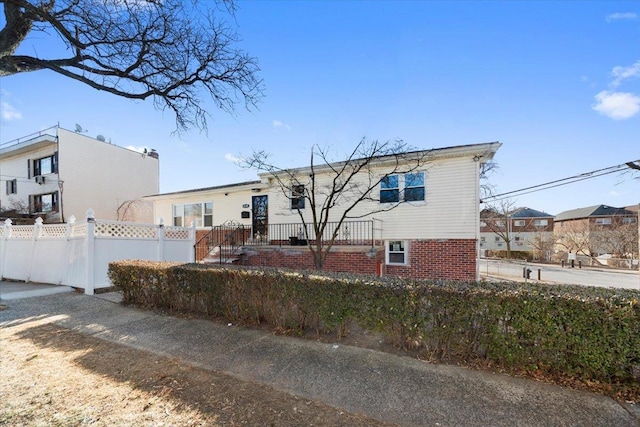 rear view of property with a fenced front yard and brick siding