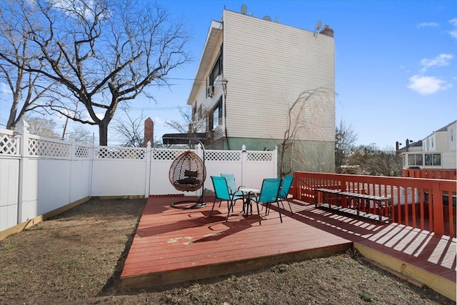 wooden deck with outdoor dining space and a fenced backyard