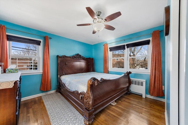 bedroom with radiator, multiple windows, baseboards, and dark wood finished floors