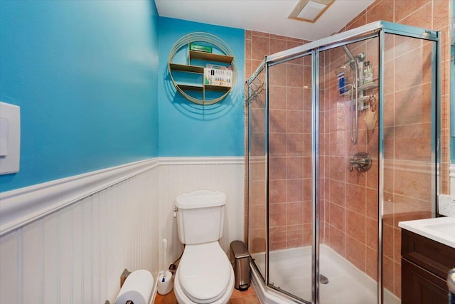 bathroom with a shower stall, wainscoting, vanity, and toilet