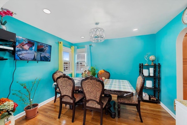 dining room featuring light wood-style floors, arched walkways, and baseboards