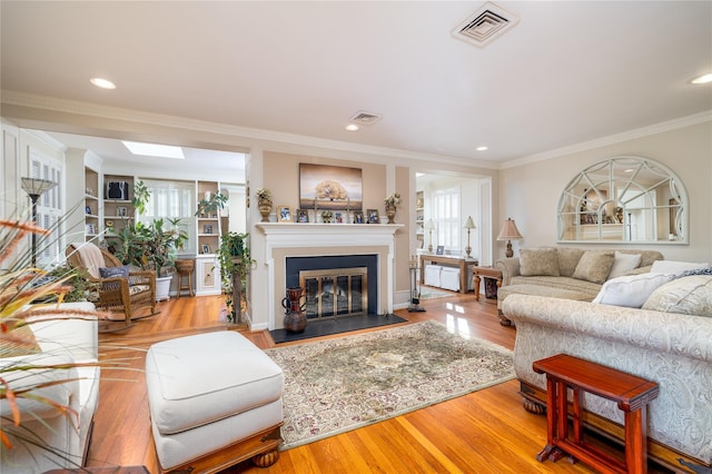 living room with a wealth of natural light, crown molding, and light hardwood / wood-style flooring