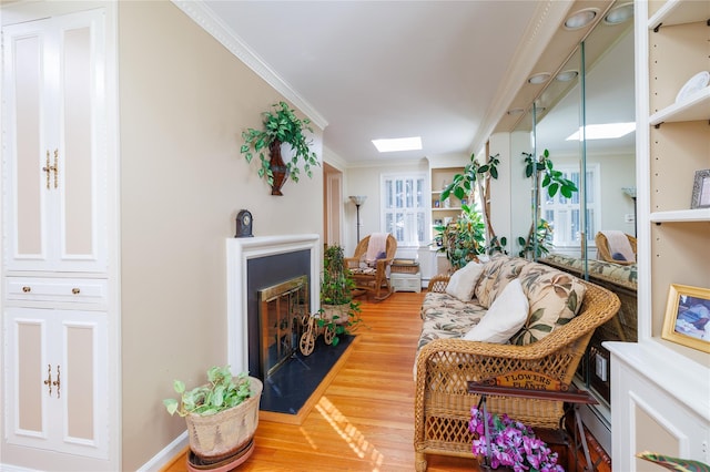 living room with a skylight, ornamental molding, and hardwood / wood-style flooring