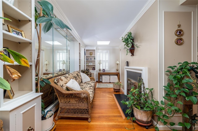 living room featuring a skylight, crown molding, a baseboard radiator, and wood-type flooring