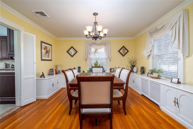 dining area with a healthy amount of sunlight, wood-type flooring, a notable chandelier, and ornamental molding