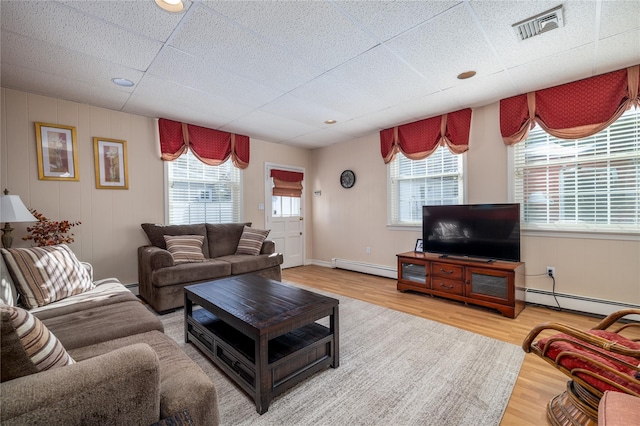 living room featuring hardwood / wood-style flooring, baseboard heating, and a paneled ceiling