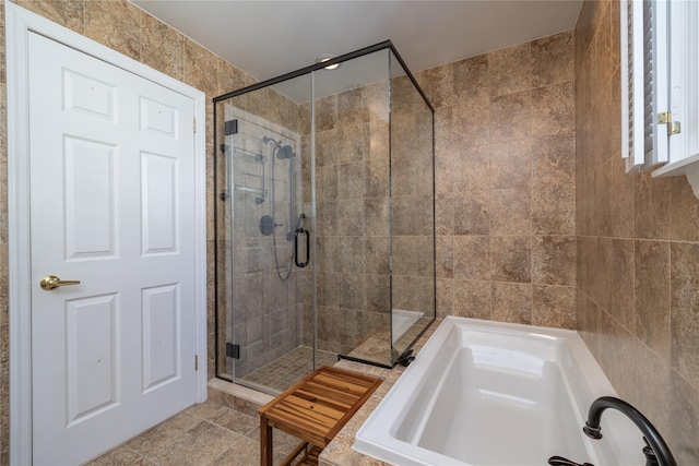 bathroom featuring independent shower and bath, tile patterned flooring, and tile walls