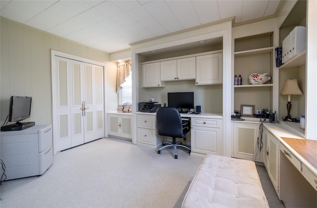 carpeted office with built in desk and crown molding