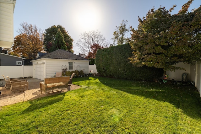 view of yard with a garage, an outbuilding, and a patio area