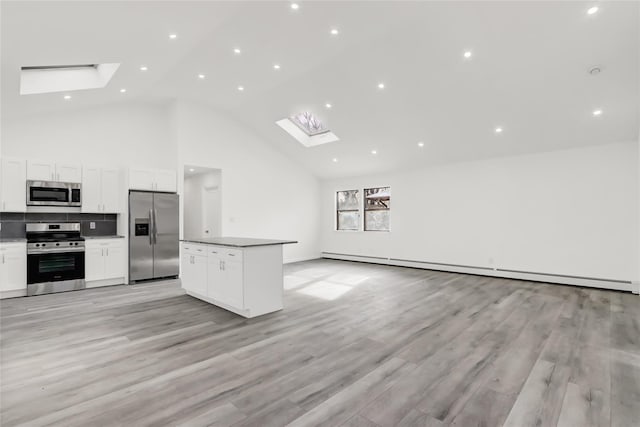 kitchen with baseboard heating, white cabinets, appliances with stainless steel finishes, a skylight, and tasteful backsplash