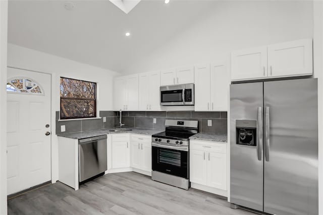 kitchen featuring decorative backsplash, light stone countertops, white cabinetry, and appliances with stainless steel finishes