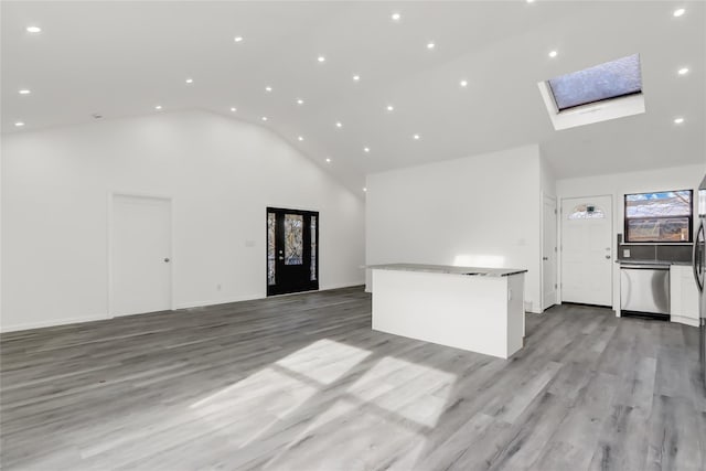 unfurnished living room with light hardwood / wood-style floors, high vaulted ceiling, and a skylight