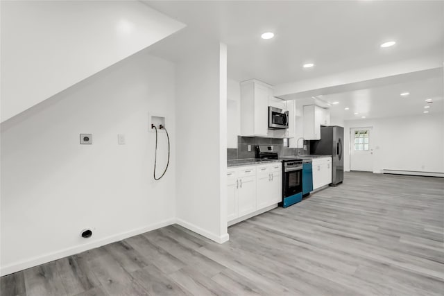 kitchen with light stone counters, white cabinets, baseboard heating, and appliances with stainless steel finishes