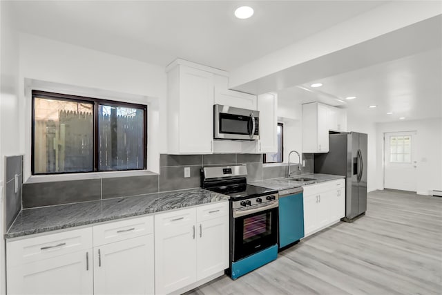 kitchen featuring appliances with stainless steel finishes, sink, white cabinetry, dark stone counters, and decorative backsplash