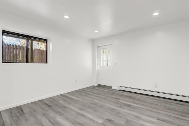 unfurnished room featuring light hardwood / wood-style floors and a baseboard radiator