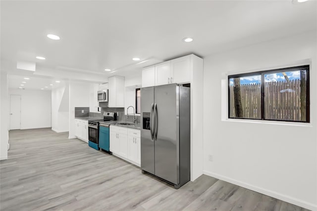 kitchen with sink, white cabinetry, light hardwood / wood-style flooring, and stainless steel appliances