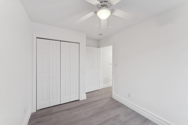 unfurnished bedroom featuring light wood-type flooring, ceiling fan, and a closet