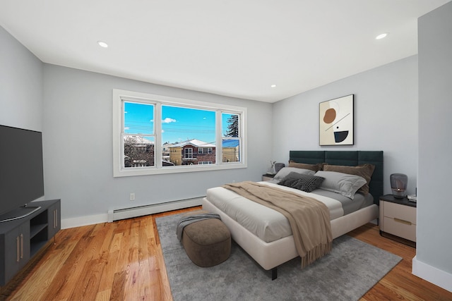 bedroom featuring baseboard heating and light hardwood / wood-style floors