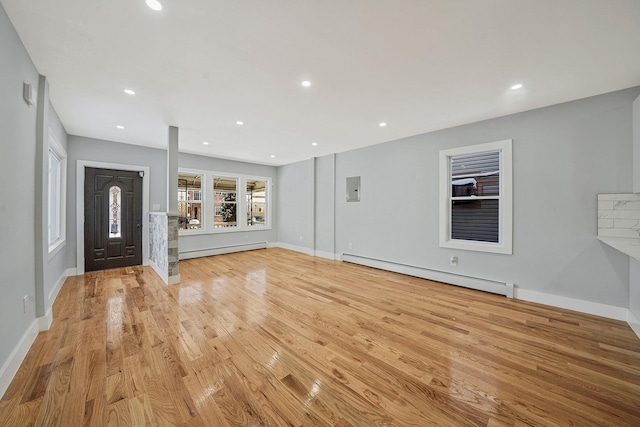 unfurnished living room with a baseboard heating unit and light hardwood / wood-style floors