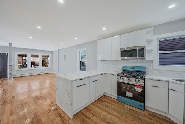 kitchen featuring baseboard heating, white cabinets, appliances with stainless steel finishes, backsplash, and kitchen peninsula