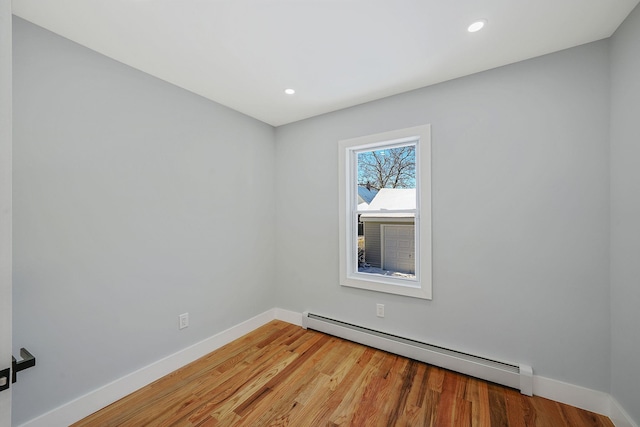 empty room featuring hardwood / wood-style flooring and a baseboard radiator